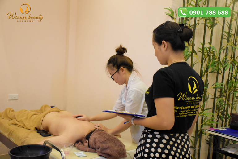 Học viên tại Winnie Academy thực hiện quy trình massage đá nóng dưới sự hỗ trợ của giảng viên 